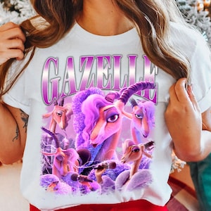 May include: White t-shirt featuring a graphic of a purple gazelle with a microphone, surrounded by other gazelles. The word "GAZELLE" is printed above the image in a purple gradient font.