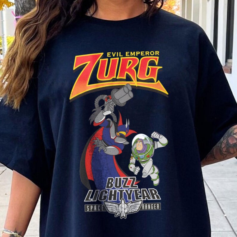 May include: Navy blue t-shirt featuring a graphic of Zurg, Buzz Lightyear, and the text "EVIL EMPEROR ZURG" in yellow and red. The shirt also has the text "BUZZ LIGHTYEAR SPACE RANGER".