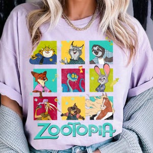 Puede incluir: Camiseta lila claro con una cuadr&iacute;cula de personajes de Zootopia en cuadrados coloridos. La palabra "ZOOTOPIA" est&aacute; impresa en verde y azul en la parte inferior. La camiseta tiene mangas cortas.