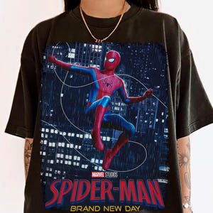 Puede incluir: Camiseta negra con un gr&aacute;fico vibrante de Spider-Man en una pose din&aacute;mica contra un fondo de ciudad. El dise&ntilde;o incluye el logotipo de Marvel Studios y el texto "SPIDER-MAN BRAND NEW DAY" en letras rojas y azules.