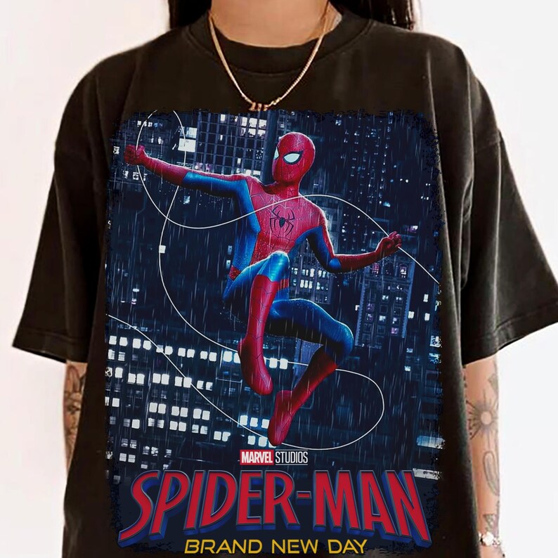 Puede incluir: Camiseta negra con un gr&aacute;fico vibrante de Spider-Man en una pose din&aacute;mica contra un fondo de ciudad. El dise&ntilde;o incluye el logotipo de Marvel Studios y el texto "SPIDER-MAN BRAND NEW DAY" en letras rojas y azules.