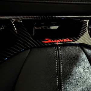 Peut inclure: Une garniture intérieure en fibre de carbone noire avec un logo "Supra" rouge.