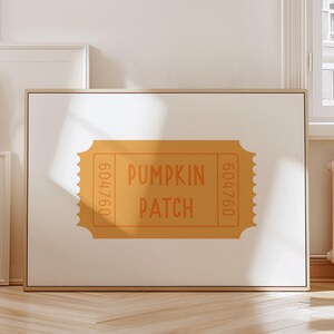 May include: A framed print featuring a pumpkin patch ticket design. The ticket is a warm orange color with the words "PUMPKIN PATCH" in a playful font. The ticket also has the number "604760" on each side. The print is displayed on a white background.