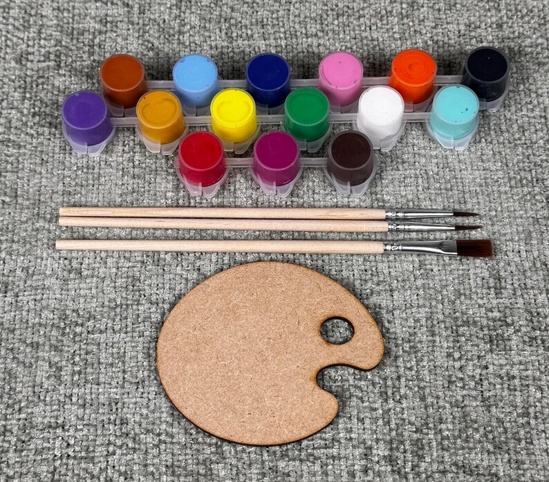 May include: A craft kit with a wooden palette, three paintbrushes, and a set of 12 colorful paint pots. The paint colors include purple, orange, blue, yellow, pink, green, white, and brown.
