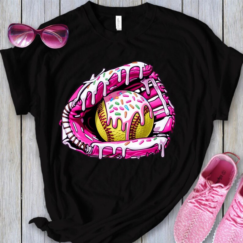 Puede incluir: Camiseta negra con un gr&aacute;fico rosa y blanco de una pelota de softball en un guante de receptor con glaseado rosa y chispas.