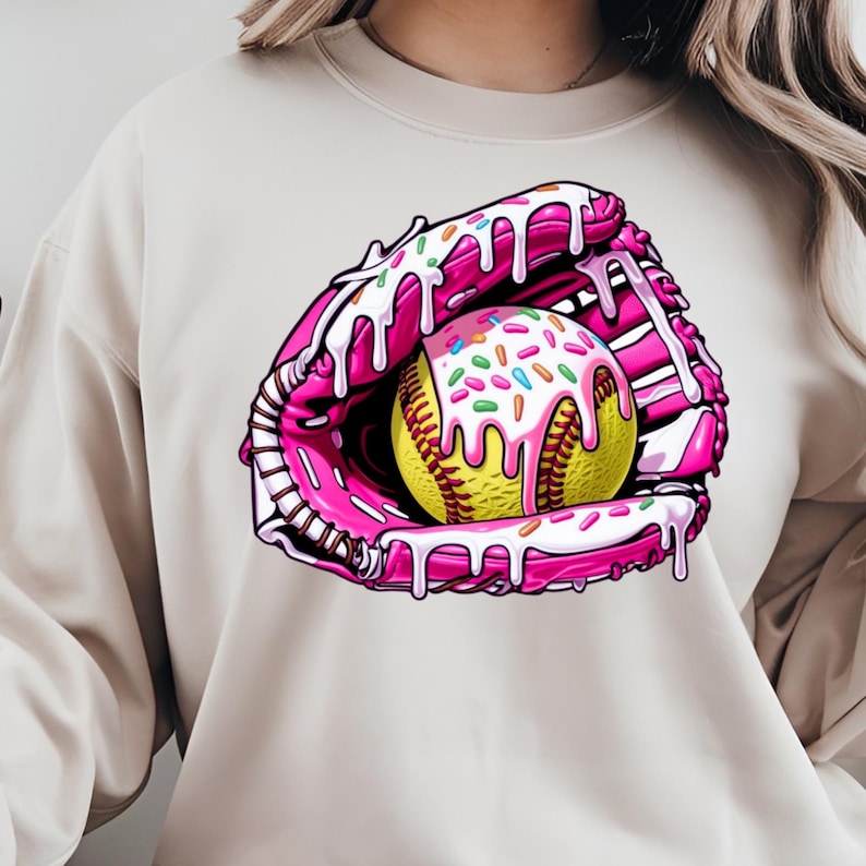 Puede incluir: Un guante de softball rosa y blanco con una pelota de softball amarilla en su interior. La pelota de softball est&aacute; cubierta de glaseado blanco y chispas de colores. El guante y la pelota de softball est&aacute;n goteando con glaseado rosa.