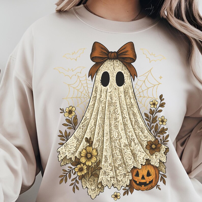 K&ouml;nnte beinhalten: Cremefarbenes Sweatshirt mit einem Geisterdesign im Vintage-Stil. Der Geist tr&auml;gt eine braune Schleife und ist mit einem spitzenartigen Laken drapiert, umgeben von Blumen, einem K&uuml;rbis, Spinnweben und Flederm&auml;usen. Ein festliches Halloween-Themen-Grafik.