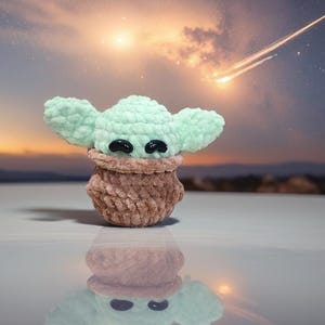 May include: A handmade crochet figure of a character with large ears and black eyes. The figure is light green with a brown base. The background features a sunset with a starry sky and a shooting star.