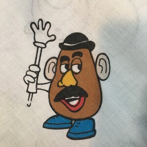 Op de afbeelding: Een cartoonillustratie van Mr. Potato Head met een zwarte bolhoed, bruine ogen, een gele neus, een zwarte snor en een rode mond. Hij draagt blauwe schoenen en houdt een witte stok vast met een hand aan het uiteinde.