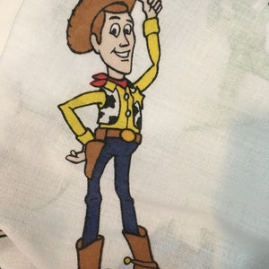 Op de afbeelding: Een cartoonillustratie van Woody uit Toy Story. Hij draagt ​​een bruine cowboyhoed, een geel shirt met een rode bandana, een bruine riem, een blauwe jeans en bruine cowboylaarzen. Hij glimlacht en geeft een duim omhoog.