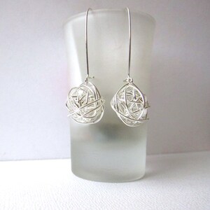 May include: A pair of silver dangle earrings with a wire mesh ball design.