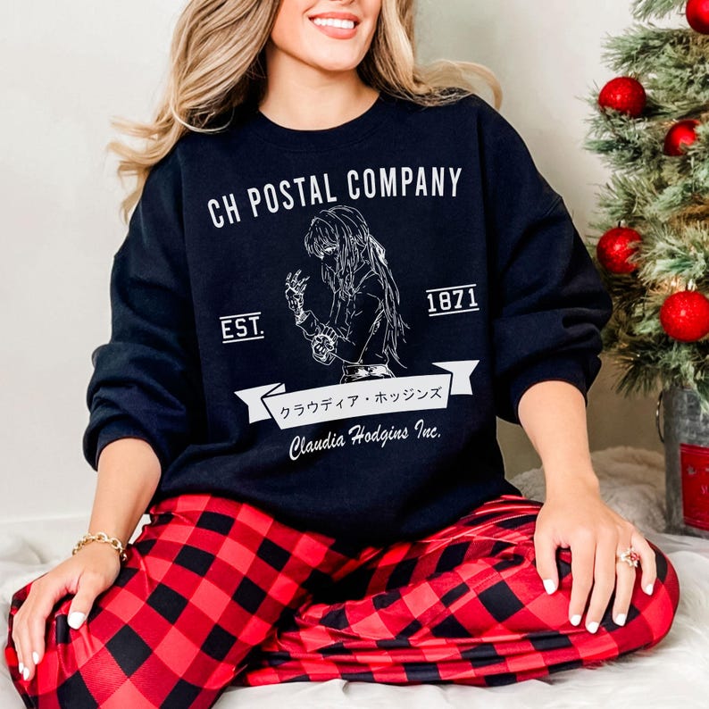 May include: A navy blue sweatshirt with the text "CH POSTAL COMPANY" and a graphic of a woman. Below the graphic are the words "EST. 1871" and Japanese text. The person is wearing red and black plaid pajama pants.
