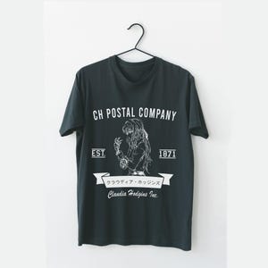 May include: Dark gray t-shirt with a white graphic. The graphic includes the text "CH POSTAL COMPANY", "EST. 1871", and Japanese text. A stylized illustration of a person is also included.