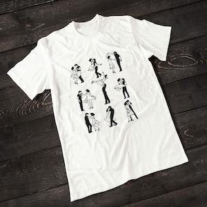 Puede incluir: Camiseta blanca con un gr&aacute;fico en blanco y negro de parejas bailando. El gr&aacute;fico presenta 9 parejas diferentes en varias poses de baile.