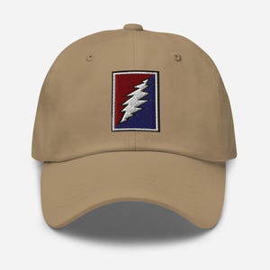 May include: A tan baseball cap with an embroidered patch featuring a lightning bolt in red, white, and blue.