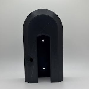 May include: A black plastic wall mount with a rectangular opening and three holes. The mount is designed to hold a device or object.