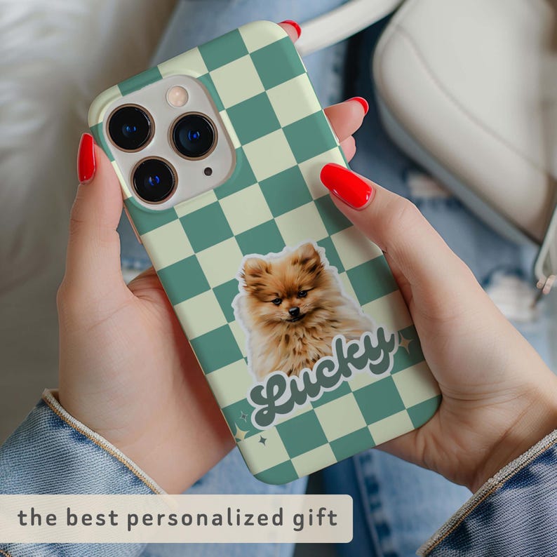 K&ouml;nnte beinhalten: Eine Handyh&uuml;lle mit gr&uuml;nem und cremefarbenem Schachbrettmuster. Auf der H&uuml;lle befindet sich ein Aufkleber eines flauschigen braunen Hundes mit dem Wort "Lucky". Der Text "the best personalized gift" steht unten.