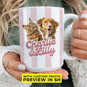 May include: White ceramic mug with pink vertical stripes, featuring a cat and dog illustration with the names "Charlie & Lilly" in pink script. The mug also has the text "WITH CUSTOM PHOTO PREVIEW IN 6H".