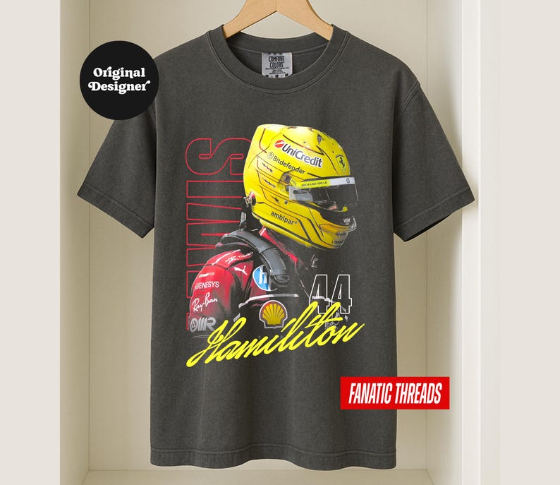 May include: Charcoal grey t-shirt with a graphic of a Formula 1 driver in a yellow helmet. The shirt displays the name "Hamilton" in yellow script, the number "44", and the text "FANATIC THREADS".