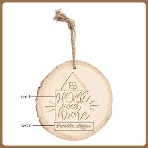 May include: A round wooden ornament with a natural wood grain finish. The ornament features the words "HOME sweet home" and "Familie Meyer" engraved within a house outline. A jute twine loop is attached for hanging.