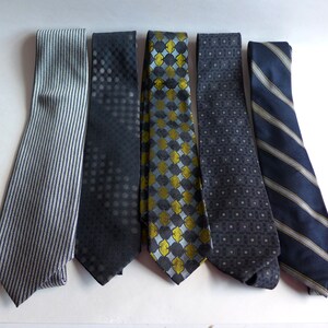 May include: Six different patterned neckties in shades of gray, blue, and yellow. The ties have various geometric and abstract designs.
