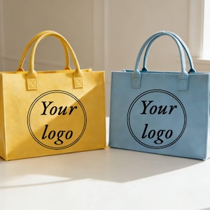May include: Two tote bags, one yellow and one light blue, with matching handles. Each bag has a circular logo area with the text "Your logo" in black. The bags are rectangular and sit on a white surface.
