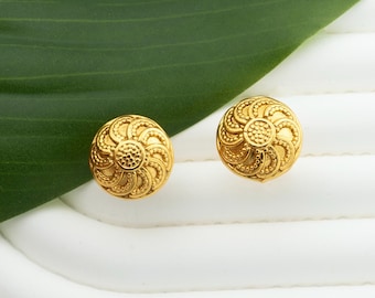 May include: A pair of gold-toned earrings with a circular design. The earrings have a textured surface and a floral pattern.
