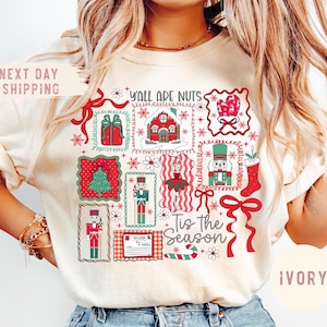 May include: Ivory-colored t-shirt featuring a festive Christmas design. The graphic includes various holiday-themed illustrations such as a Christmas tree, gift boxes, and nutcrackers, along with the text "Y'all Are Nuts" and "Tis the Season".