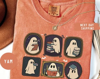 May include: Orange Comfort Colors t-shirt featuring six framed illustrations of ghosts reading books. The illustrations are in a variety of frames with a night sky, books, and candles. A gold necklace and the text "NEXT DAY SHIPPING" are also visible.
