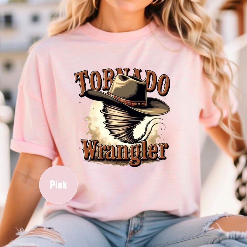 Op de afbeelding: Roze T-shirt met een afbeelding van een tornado die een cowboyhoed draagt en de tekst "Tornado Wrangler".