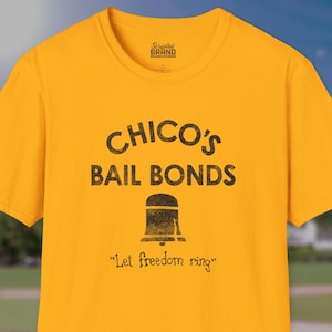 May include: Yellow t-shirt with a black graphic that says "Chico's Bail Bonds" with a bell and the text "Let freedom ring".