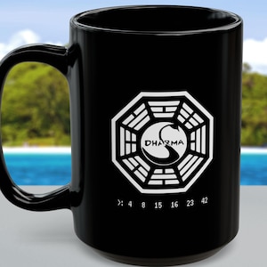 May include: Black ceramic coffee mug featuring a white Dharma Initiative logo and numbers. The logo depicts a white swan and the text "DHARMA" within a white octagon.