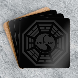 May include: A set of four black square coasters featuring the Dharma Initiative logo. The logo is a swan within an octagonal frame, with the word "DHARMA" beneath. They are stacked on a light brown cork base.