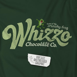 Puede incluir: Camiseta verde oscuro con un gráfico desgastado de "Whizzo Chocolate Co." con una rana de dibujos animados y el texto "home of the crunchy frog". Un gráfico de papel rasgado dice "Vintage Distressed Graphic."