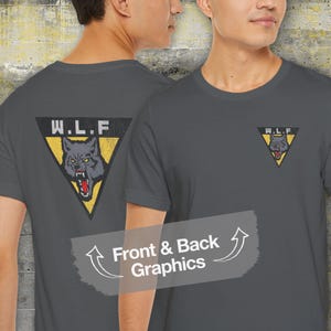 May include: A dark gray t-shirt with a yellow triangle graphic featuring a wolf's head and the letters "W.L.F." The graphic is on the back of the shirt. The front of the shirt has a smaller version of the graphic on the left chest.