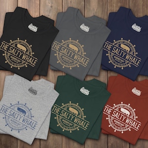 Six folded 'The Salty Whale' vintage distressed pub logo t-shirt inspired by Widow's Bay Apple TV series, soft Bella+Canvas cotton tee