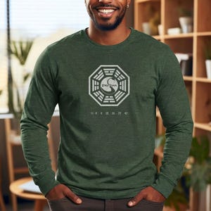 May include: Green long-sleeved shirt with a white Dharma Initiative logo and the numbers 4 8 15 16 23 42. The shirt is made of a soft material.
