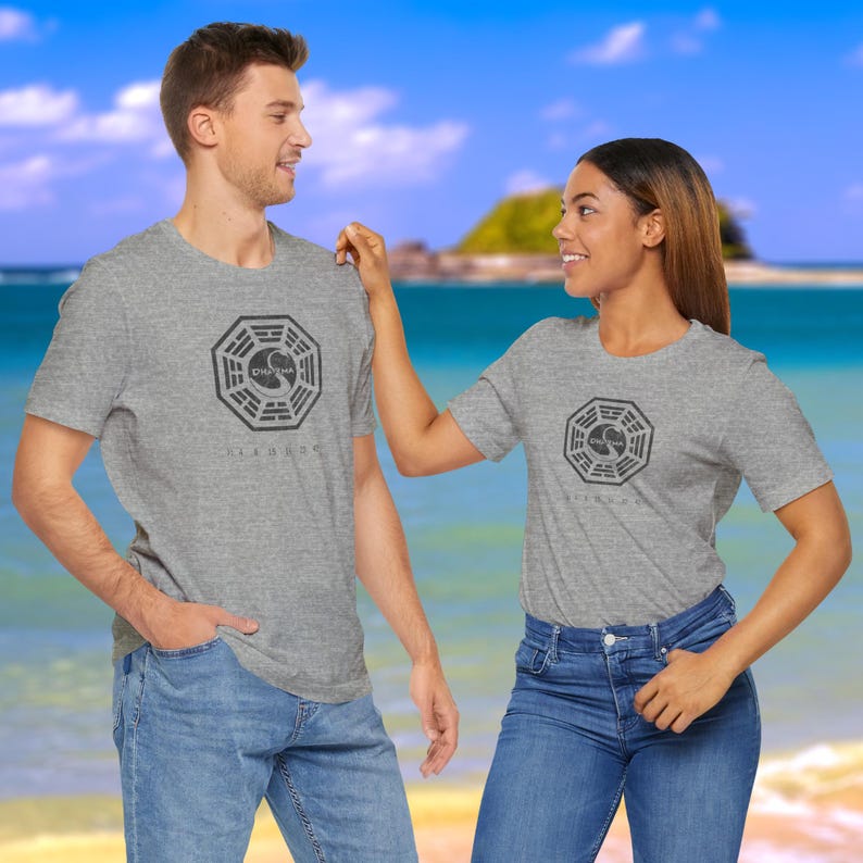 Models wearing heather grey short-sleeve t-shirts featuring the Dharma Initiative swan logo graphic from the TV show LOST in a vintage distressed style.