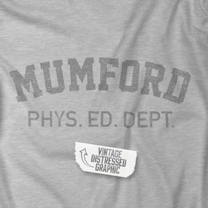 Puede incluir: Una camiseta gris con un estampado gráfico vintage desgastado que dice "MUMFORD PHYS. ED. DEPT."