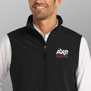 Puede incluir: Chaleco negro con cremallera completa y cuello alzado. El logotipo de Axe Capital, en blanco y rojo, está presente. La persona lleva una camisa blanca con cuello debajo del chaleco.