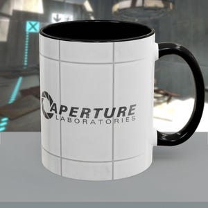 Peut inclure: Mug en céramique blanche avec intérieur et anse noirs. Le mug présente le logo Aperture Laboratories en noir et gris, sur un fond blanc carrelé. Le mug est conçu pour les boissons chaudes.