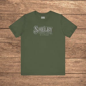 Military green Bella+Canvas 3001 t-shirt featuring a vintage Shelby Company Limited logo from Peaky Blinders.