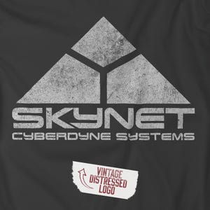Puede incluir: Una camiseta negra con un gráfico blanco desgastado del logotipo de Skynet. El logotipo tiene una forma triangular con el texto "Skynet" y "Cyberdyne Systems" debajo.
