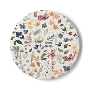 May include: A round, off-white floral design featuring watercolor-style flowers in shades of pink, orange, blue, and purple. The design includes various flower types and green leaves, creating a natural, botanical theme.