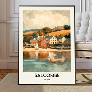 May include: A framed art print of Salcombe, Devon. The artwork depicts a coastal village with colorful buildings, sailboats on the water, and rolling hills in the background. The print has a vintage aesthetic with the text "SALCOMBE DEVON" at the bottom.