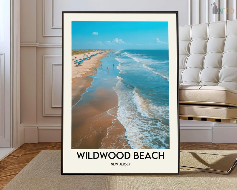 May include: A framed print depicting a coastal scene. The image shows a sandy beach with ocean waves, blue parasols, and figures. The sky is a clear blue. The text "Wildwood Beach, New Jersey" is at the bottom of the print.