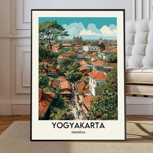 Puede incluir: Una impresión artística enmarcada que presenta una ilustración de Yogyakarta, Indonesia. La obra muestra un paisaje urbano con tejados rojos, vegetación exuberante y un cielo azul brillante. El texto "YOGYAKARTA INDONESIA" se muestra en la parte inferior.