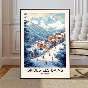May include: A framed art print featuring a winter landscape with snow-covered mountains and a village. The artwork depicts skiers on a slope and the text "BRIDES-LES-BAINS SKI RESORT" at the bottom. The color palette includes blues, whites, and oranges.