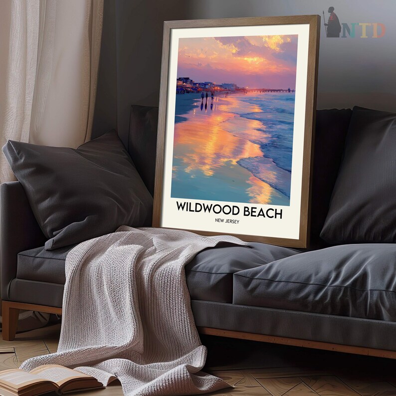 K&ouml;nnte beinhalten: Ein gerahmter Druck mit einer Strandszene bei Sonnenuntergang. Das Kunstwerk zeigt einen lebendigen Himmel mit orangefarbenen und rosa Farbt&ouml;nen, die sich im nassen Sand spiegeln. Der Text "Wildwood Beach, New Jersey" ist unten auf dem Bild gedruckt.