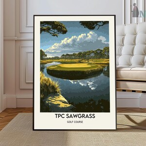 May include: A framed poster with a scenic view of a golf course. The poster features a green golf course with a body of water in the foreground. The sky is blue with white clouds. The poster has the text "TPC Sawgrass Golf Course" at the bottom.
